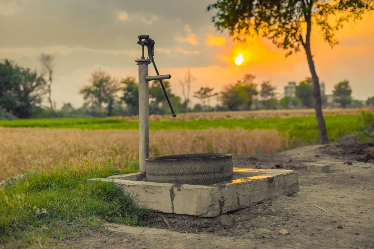 Vintage water pump in a countryside field at golden hour, a rural well water scene