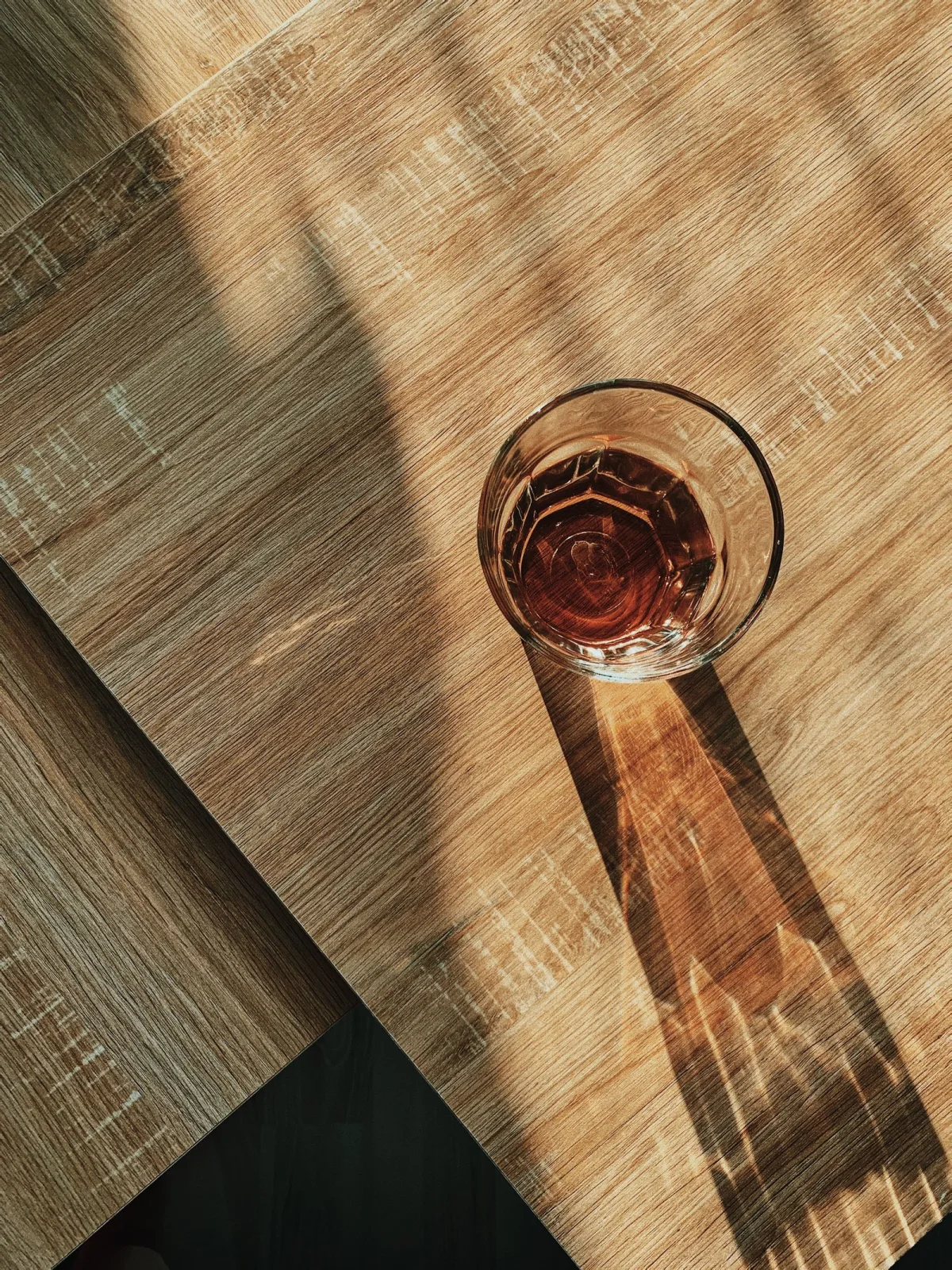 A clear glass of water glowing in warm natural sunlight on a wooden table