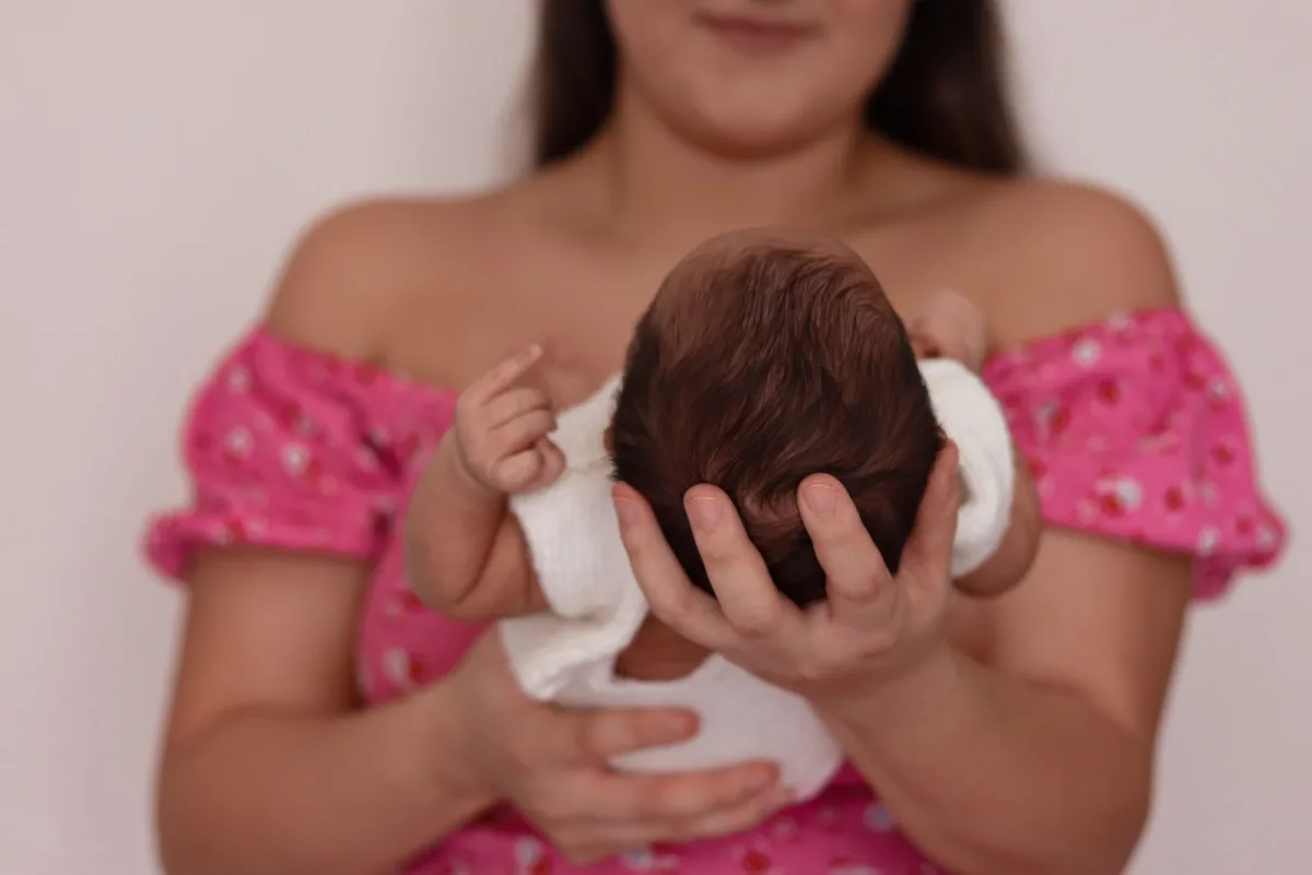 A parent gently cradling a newborn baby, a tender moment of early care