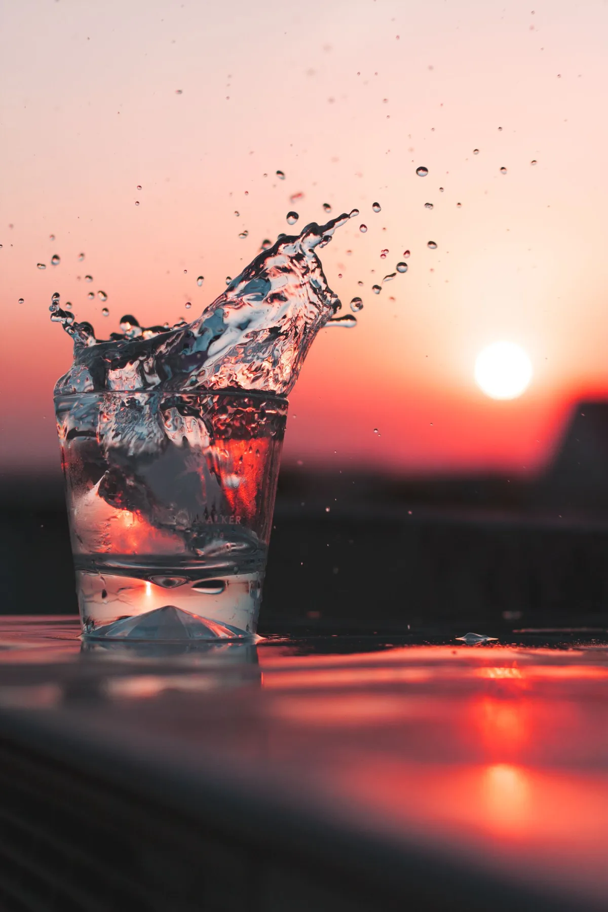 A glass of water glowing against a warm golden sunset, held to the light