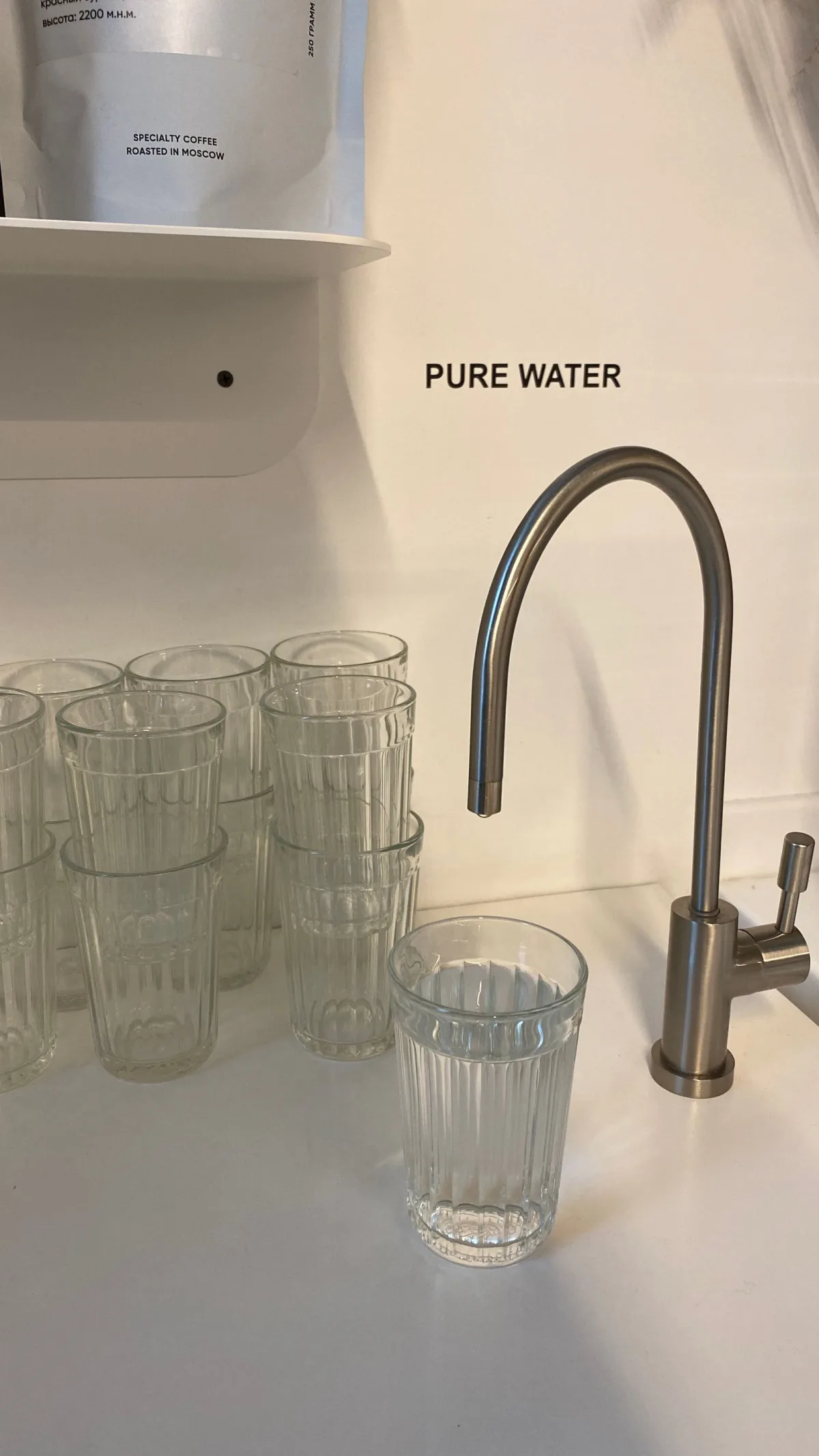 A clear glass filling with pure water at a bright kitchen faucet