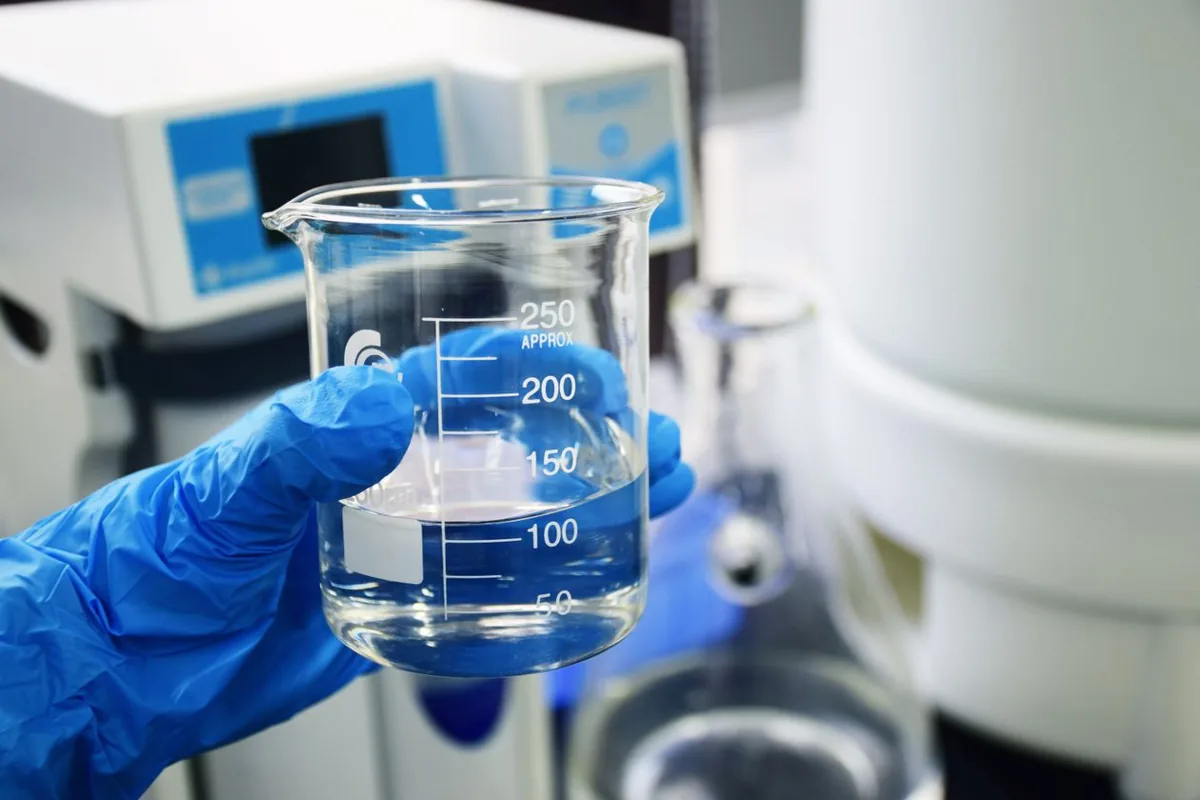 Gloved hand testing water in a lab beaker