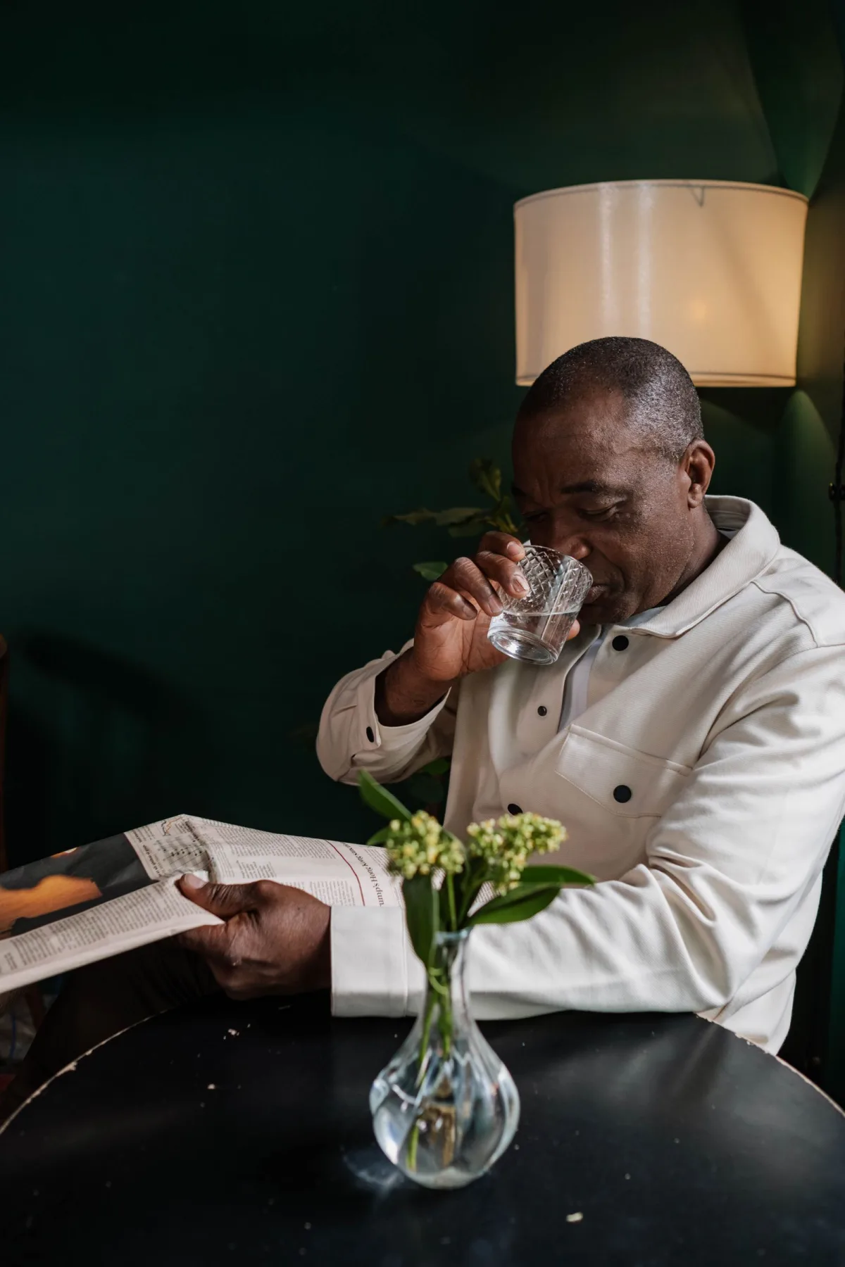 A man drinking a glass of water at home in warm morning light